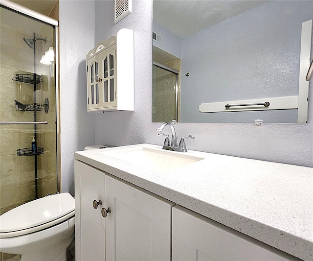 bathroom featuring a shower with door, vanity, and toilet