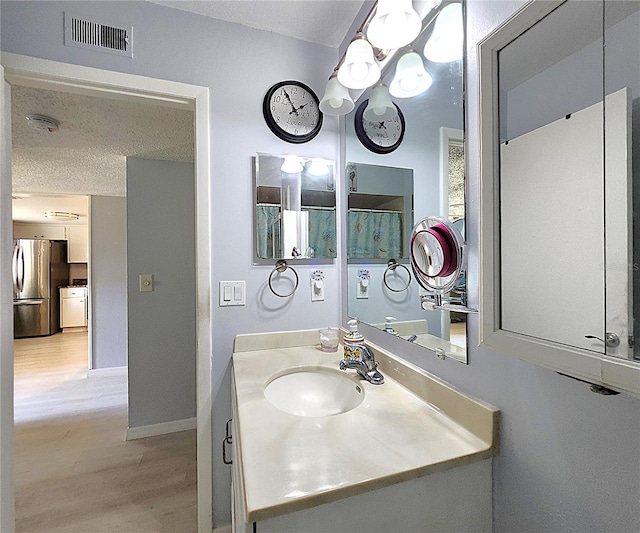 bathroom featuring vanity, hardwood / wood-style floors, and a textured ceiling