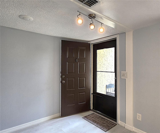 entryway featuring light hardwood / wood-style flooring and a textured ceiling