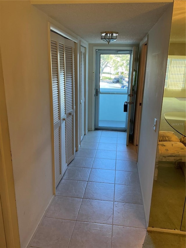 corridor with a textured ceiling and light tile patterned flooring