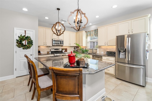 kitchen with a center island, hanging light fixtures, light tile patterned floors, dark stone countertops, and stainless steel appliances