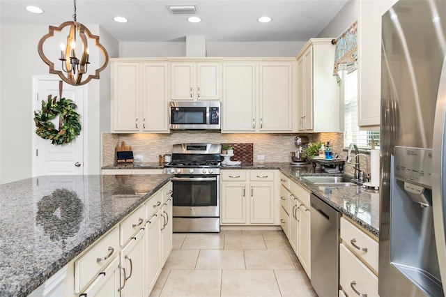 kitchen featuring sink, decorative light fixtures, dark stone counters, and appliances with stainless steel finishes