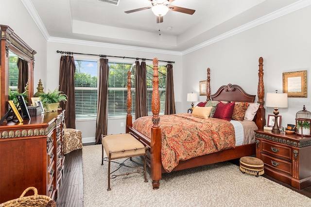 bedroom with hardwood / wood-style flooring, ceiling fan, ornamental molding, and a raised ceiling