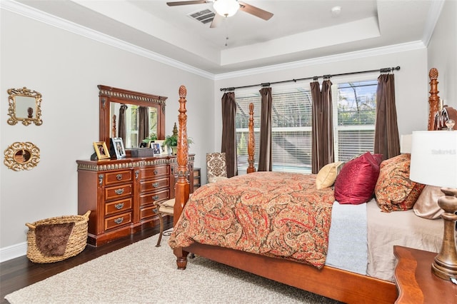 bedroom with dark hardwood / wood-style flooring, ornamental molding, ceiling fan, and a tray ceiling