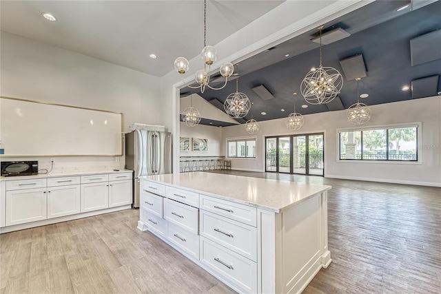 kitchen with white cabinetry, lofted ceiling, a center island, and stainless steel fridge