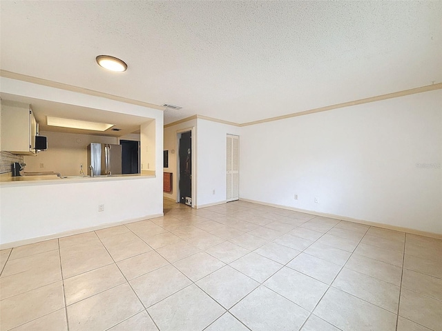 tiled spare room with a textured ceiling and ornamental molding