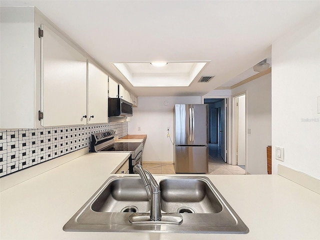 kitchen with backsplash, a raised ceiling, sink, white cabinetry, and stainless steel appliances