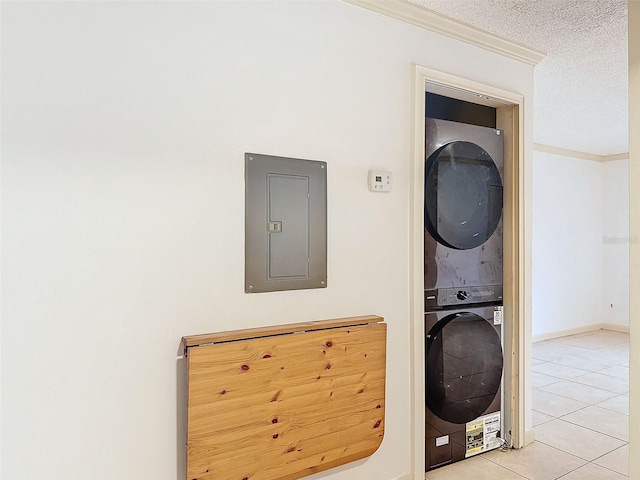 laundry room with electric panel, stacked washer and clothes dryer, crown molding, and light tile patterned flooring