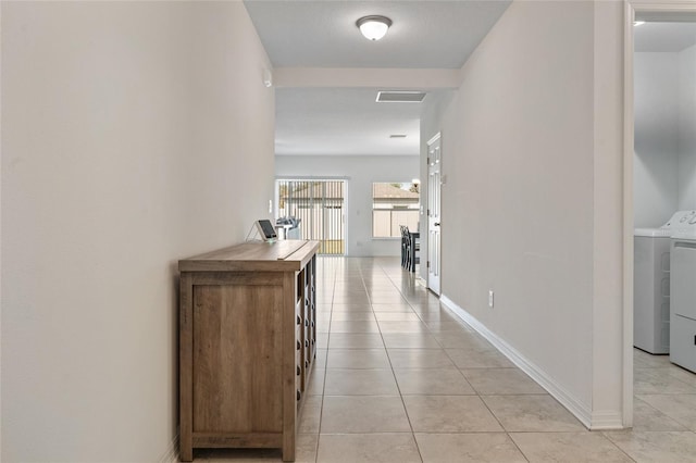 hall featuring light tile patterned floors and washer / dryer