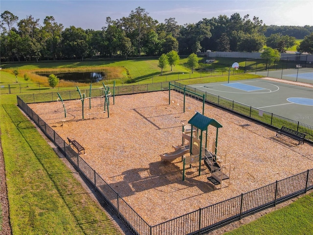 view of home's community featuring basketball hoop, a water view, a playground, and a yard