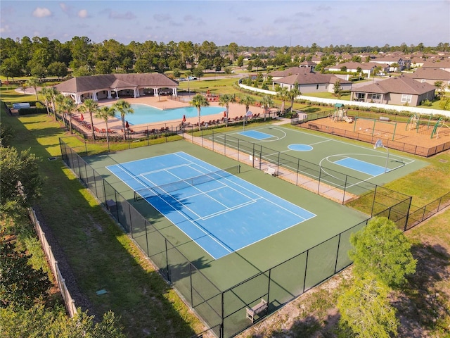 view of sport court with basketball hoop and a yard