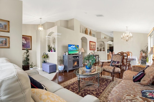 living room featuring a fireplace, wood-type flooring, vaulted ceiling, and a notable chandelier