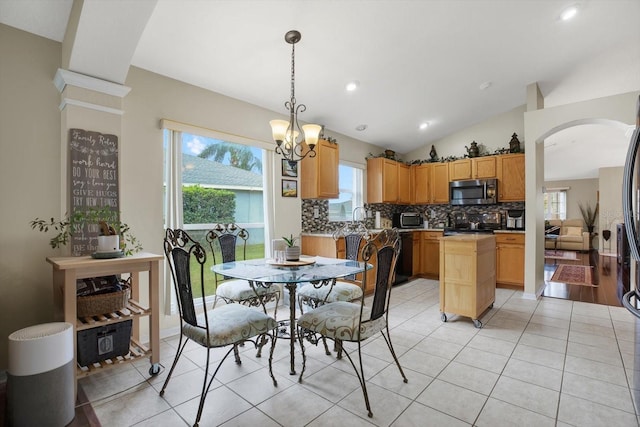 tiled dining room featuring vaulted ceiling, a notable chandelier, and sink