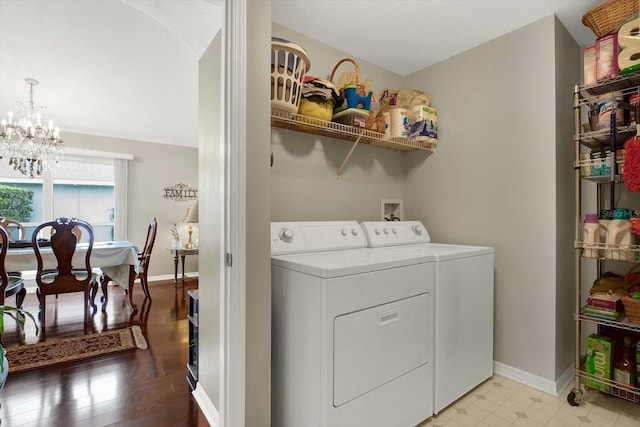 clothes washing area with light hardwood / wood-style floors, washer and dryer, and a notable chandelier