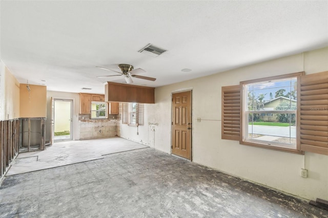 unfurnished living room featuring ceiling fan and a wealth of natural light