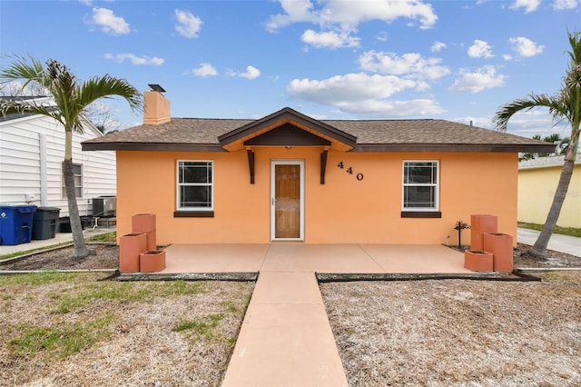 440 77th Ave, St Pete Beach, FL 33706 - bungalow featuring stucco siding, a patio area, a chimney, and a shingled roof
