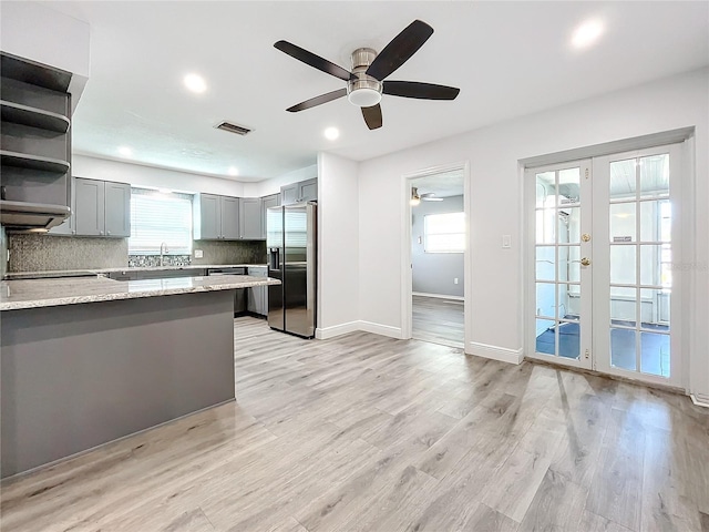 kitchen with ceiling fan, french doors, light stone countertops, stainless steel refrigerator with ice dispenser, and decorative backsplash