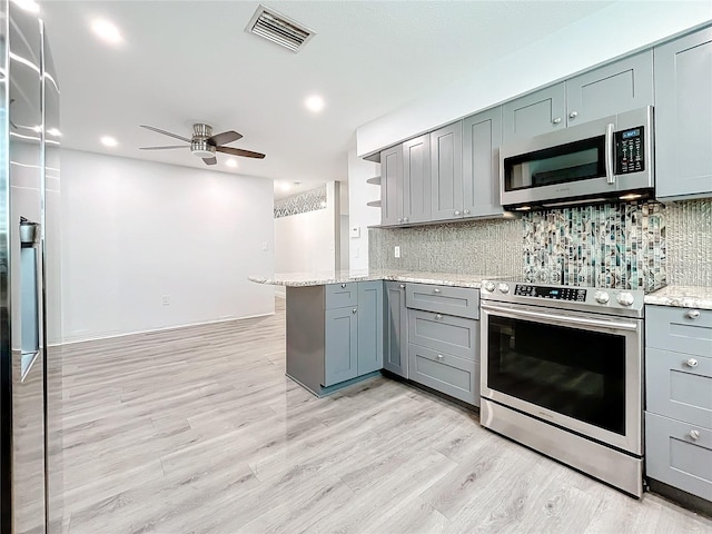 kitchen with kitchen peninsula, ceiling fan, light wood-type flooring, and appliances with stainless steel finishes