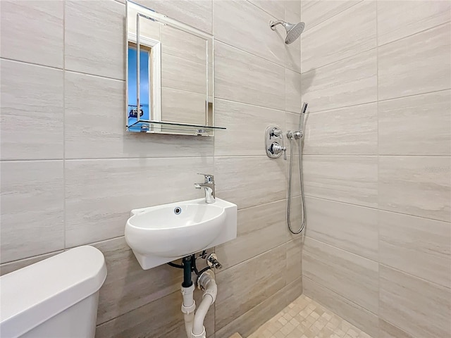 bathroom featuring tiled shower, sink, and toilet