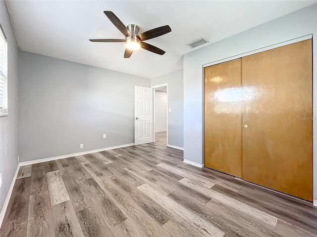 unfurnished bedroom with hardwood / wood-style floors, ceiling fan, and a closet