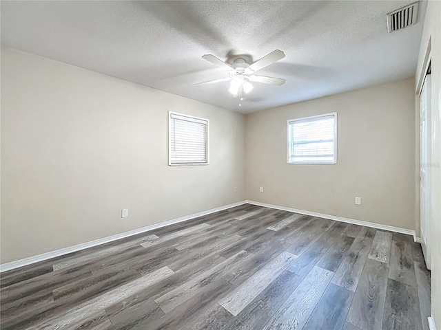 empty room with a textured ceiling, ceiling fan, and dark hardwood / wood-style floors