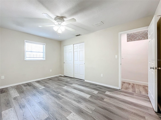 unfurnished bedroom with a closet, ceiling fan, light hardwood / wood-style flooring, and a textured ceiling