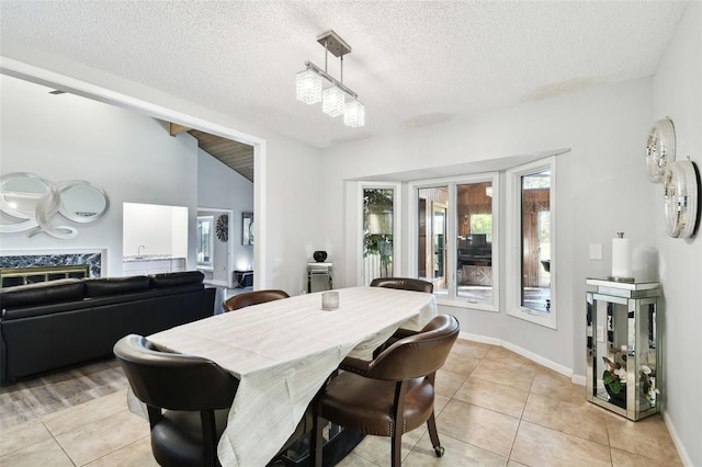 dining area with light tile patterned floors, a textured ceiling, lofted ceiling, and a premium fireplace