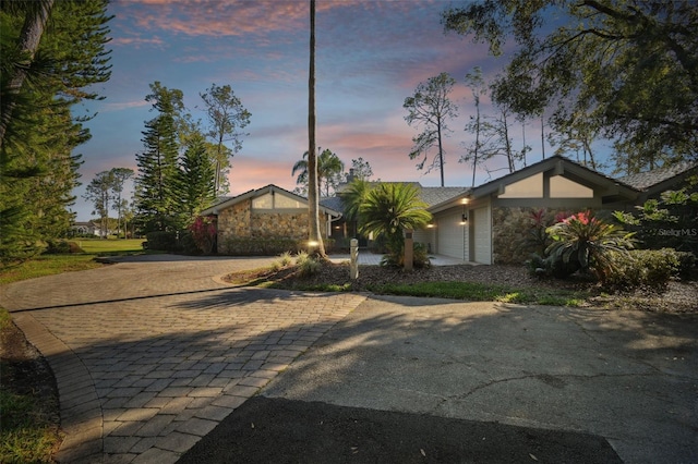 5474 Kemkerry Rd, Wesley Chapel, FL 33543 - mid-century modern home with driveway, an attached garage, and stone siding