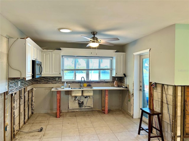 kitchen with decorative backsplash, ceiling fan, sink, light tile patterned floors, and white cabinetry