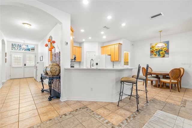 kitchen with french doors, light brown cabinets, white refrigerator with ice dispenser, kitchen peninsula, and light tile patterned floors