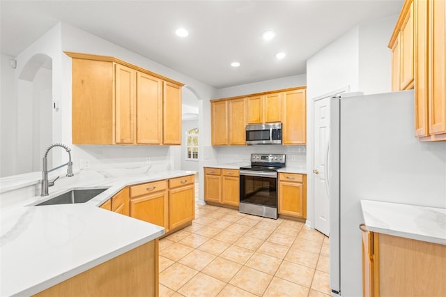 kitchen with sink, light brown cabinets, stainless steel appliances, tasteful backsplash, and light tile patterned floors