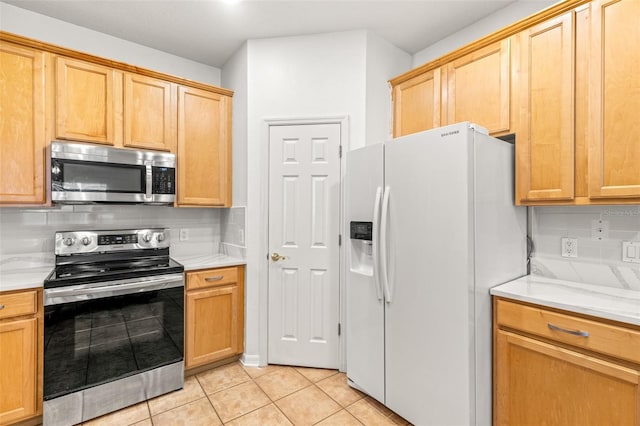 kitchen with backsplash, light tile patterned floors, and stainless steel appliances