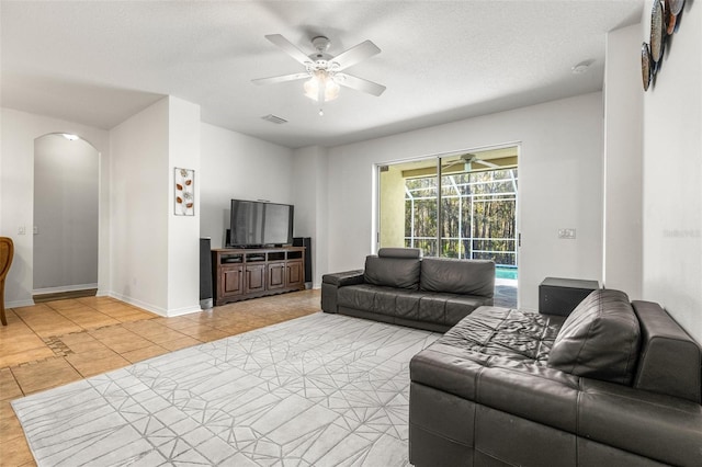 living room featuring ceiling fan, light tile patterned floors, and a textured ceiling