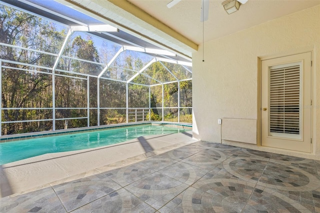 view of pool featuring glass enclosure, ceiling fan, and a patio