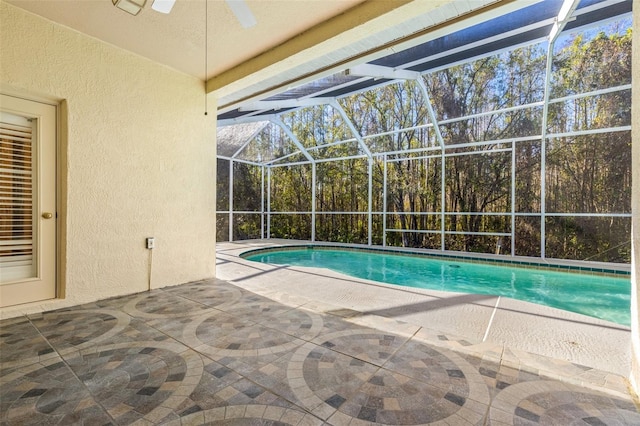 view of pool with glass enclosure, ceiling fan, and a patio area