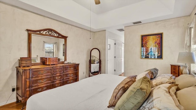 bedroom featuring a raised ceiling, wood-type flooring, and ceiling fan