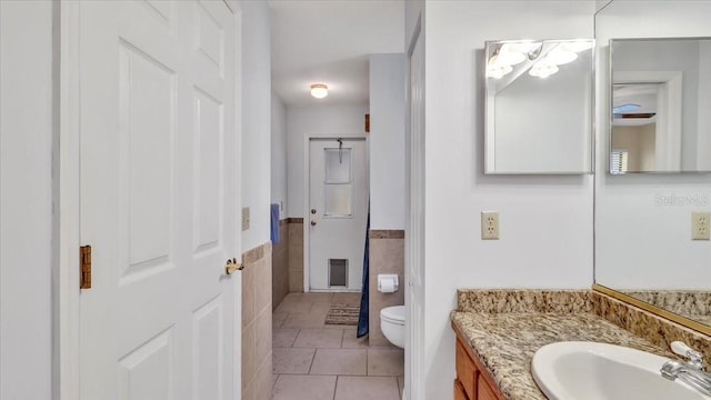 bathroom featuring vanity, tile walls, tile patterned floors, and toilet