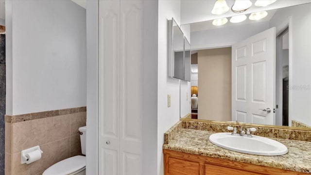 bathroom with vanity, tile walls, and toilet