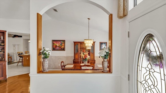 entryway with vaulted ceiling, parquet flooring, and a chandelier