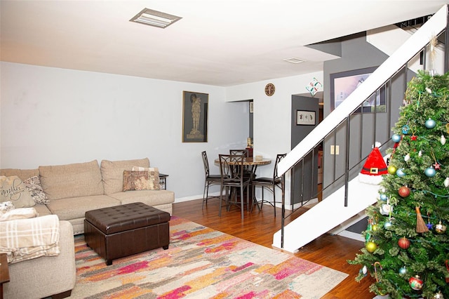 living area featuring stairs, wood finished floors, visible vents, and baseboards