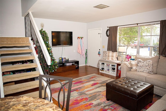 living area with stairs, wood finished floors, visible vents, and baseboards