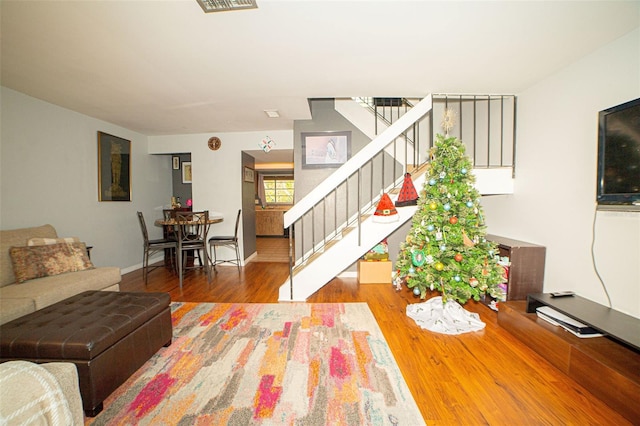 living room with baseboards, wood finished floors, and stairs