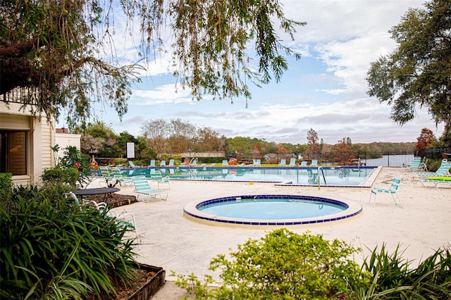 pool with a community hot tub, a patio, and fence