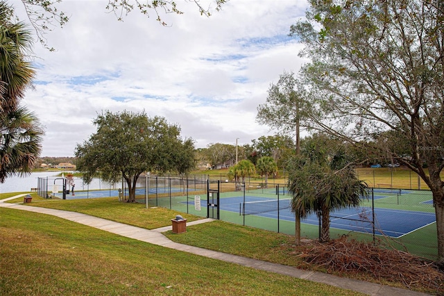 view of sport court featuring a water view, a lawn, and fence