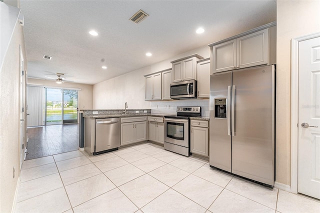 kitchen with gray cabinetry, sink, ceiling fan, light tile patterned floors, and appliances with stainless steel finishes