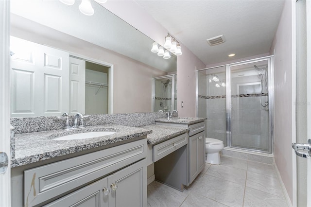 bathroom with tile patterned floors, vanity, toilet, and a shower with door