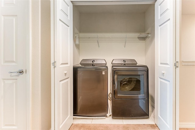 clothes washing area with light tile patterned floors and separate washer and dryer