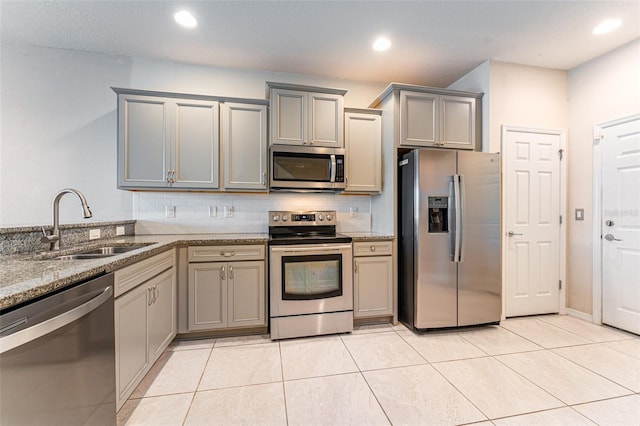 kitchen with decorative backsplash, stainless steel appliances, sink, light tile patterned floors, and gray cabinets