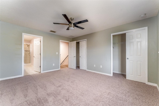 unfurnished bedroom with light carpet, ensuite bath, ceiling fan, and multiple closets