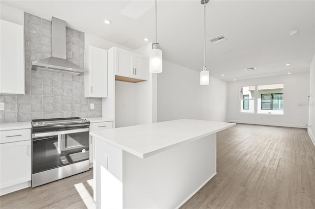 kitchen with pendant lighting, white cabinetry, stainless steel electric range oven, and wall chimney range hood